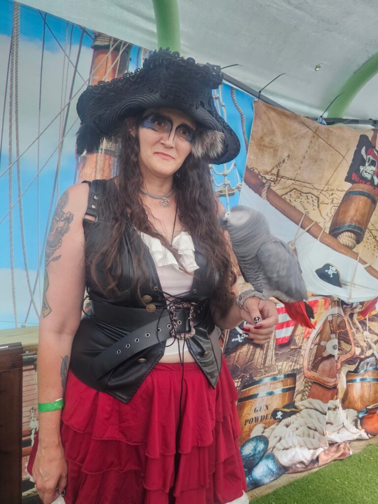 Me at the Virginia Renaissance Faire holding a parrot on my hand—dressed in period style, fully immersed in the festive, whimsical atmosphere